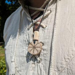 Collier viking avec pendentif en bois gravé d'un heaume de terreur ornementé par une couronne de runes.