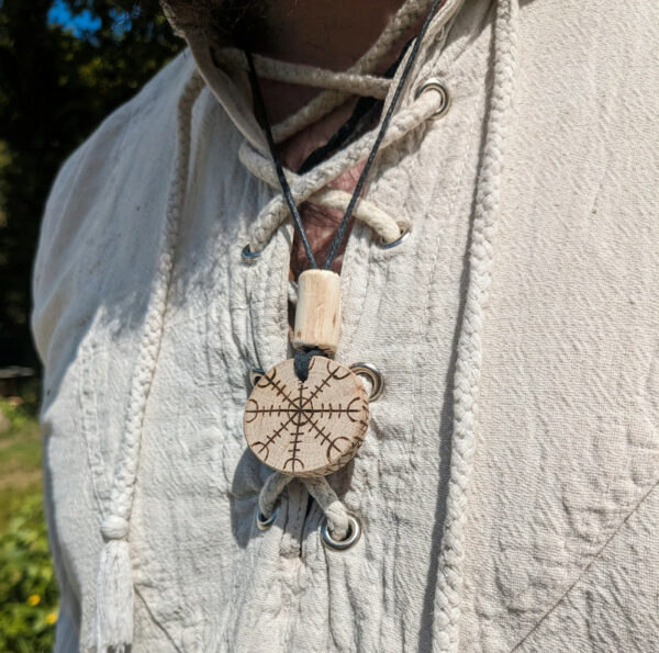 Collier viking avec pendentif en bois gravé d'un heaume de terreur ornementé par une couronne de runes.